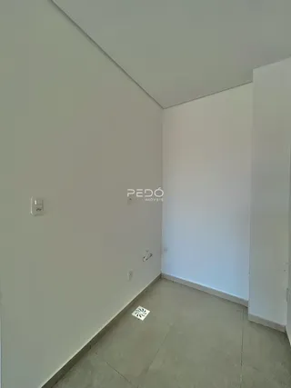 Vista de um corredor interno com paredes brancas e piso de cerâmica.