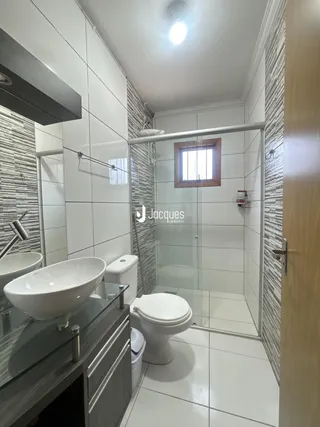 Banheiro moderno com revestimento de azulejos e box de vidro.