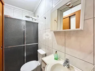 O interior de um banheiro com revestimento de azulejos claros e louças sanitárias brancas.