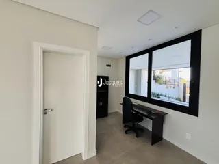 Hall de entrada com porta branca e janela escura em um imóvel.