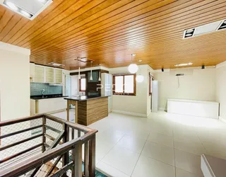 Ambiente interno de uma sala de estar com piso de madeira e cozinha integrada.