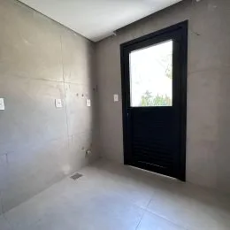 Foto de um corredor interno com paredes lisas e uma porta escura.