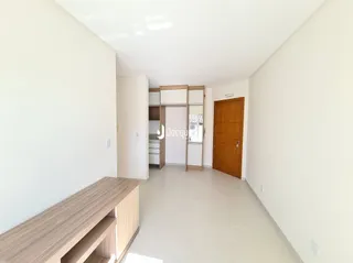 A foto mostra um corredor interno com paredes brancas e piso claro.