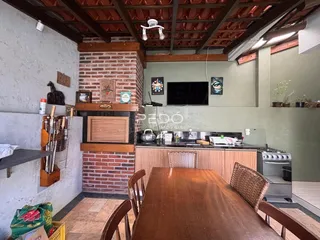 Interior de uma sala de estar com lareira de tijolos e teto de madeira.