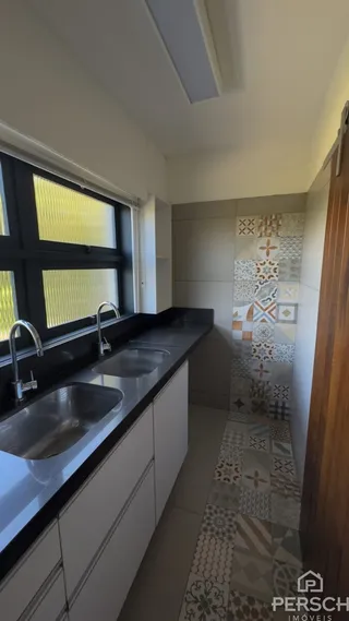 Vista de uma bancada de cozinha com pias e armários brancos.
