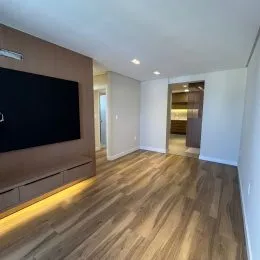 Sala de estar com piso de madeira e painel decorativo na parede.