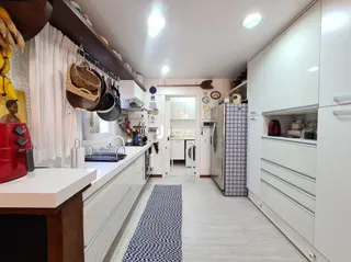 Cozinha moderna com armários brancos e piso claro.