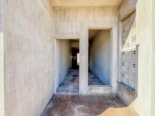 Corredor interno de uma residência com paredes de concreto aparente.