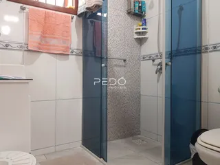 Foto de um banheiro com revestimento cerâmico e box de vidro.