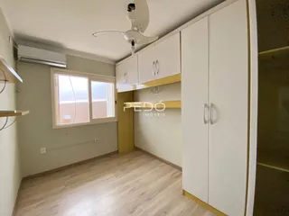 A sala apresenta paredes claras e piso de madeira com armários embutidos.