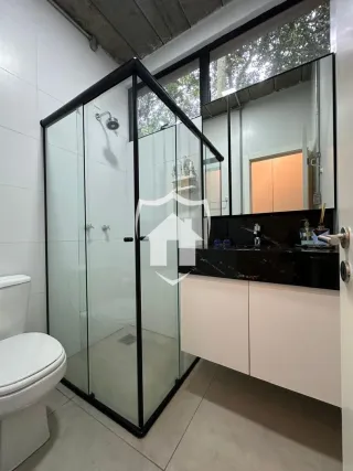 Foto de um banheiro com box de vidro e vaso sanitário.