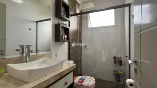 Banheiro moderno com box de vidro e bancada de mármore.