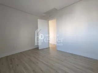 Uma sala de estar com piso de madeira clara e paredes brancas.