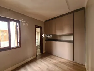 A sala de estar exibe um ambiente com piso de madeira e armários embutidos.