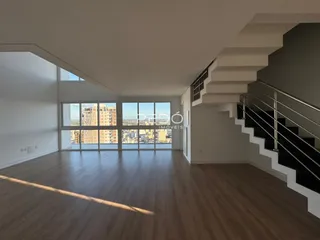 Sala de estar ampla com vista para a cidade através de grandes janelas.