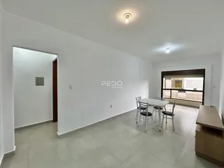 Ambiente interno de uma sala com mesa de jantar e porta de acesso.