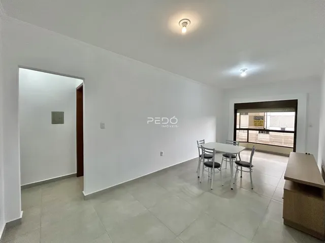 Ambiente interno de uma sala com mesa de jantar e porta de acesso.