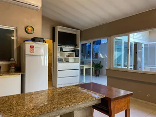 Foto de uma área de estar com bancada e eletrodomésticos brancos.