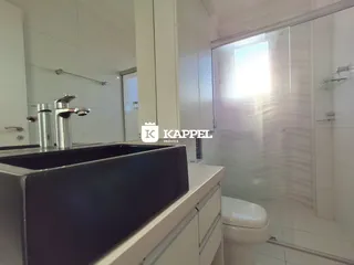 Banheiro com bancada e box de vidro em um imóvel.