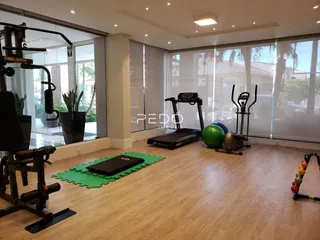 Imagem de uma sala com equipamentos de ginástica e piso de madeira.