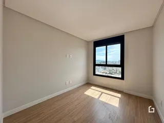 Uma sala com piso de madeira e grande janela com vista da cidade.