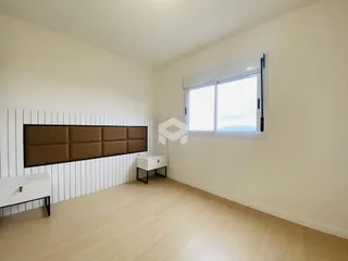 Quarto com parede de painel branco e piso de madeira clara.