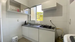 Cozinha moderna com armários brancos e piso claro.