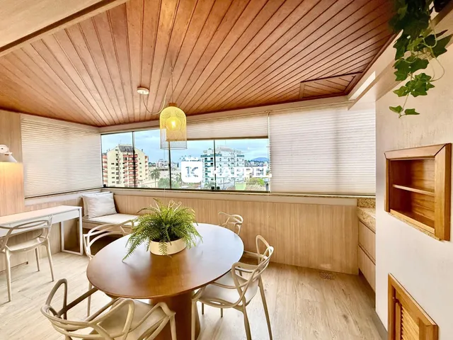 Sala de jantar com mesa redonda de madeira e vista da cidade.