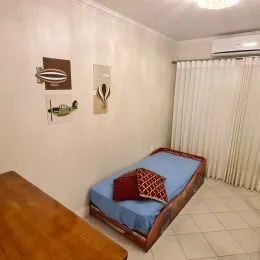 Um quarto com cama azul e cortinas brancas é mostrado na propriedade.