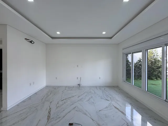 Sala ampla com piso de mármore e grandes janelas.