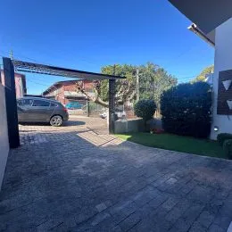 Vista externa de uma área pavimentada com vegetação e paisagismo.