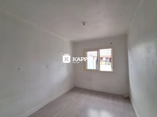 Foto de um cômodo interno com paredes brancas e uma janela que dá para o exterior.