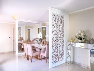Sala de jantar com mesa e cadeiras em um ambiente claro e bem iluminado.