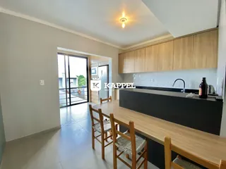 A cozinha apresenta armários de madeira e uma bancada escura.