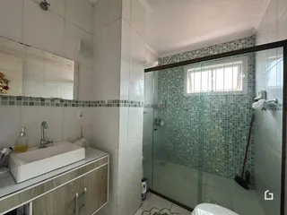 Foto de um banheiro com revestimento cerâmico e box de vidro.