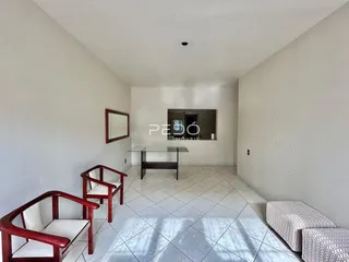 Sala de estar com piso de cerâmica e cadeiras de madeira.