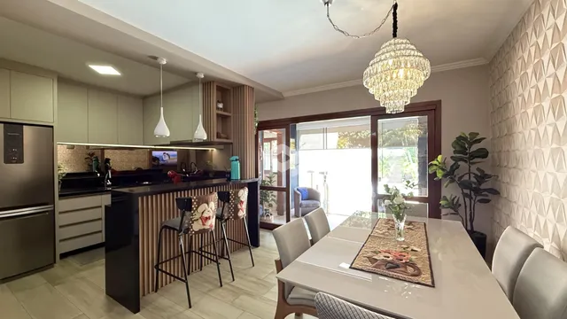 Imagem de uma cozinha moderna com ilha e área de jantar em Lajeado.