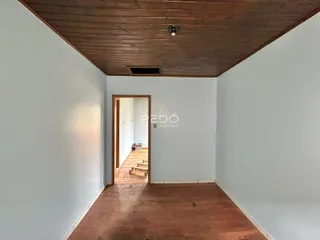 Vista de um corredor interno com teto de madeira e porta aberta.