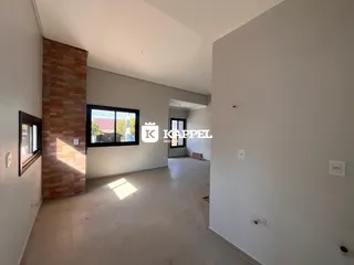Hall de entrada com parede de tijolos aparentes e piso de concreto.