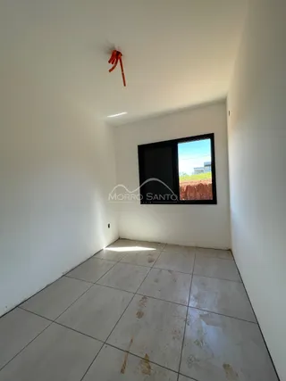 Foto de um corredor interno com piso de cerâmica e uma janela.