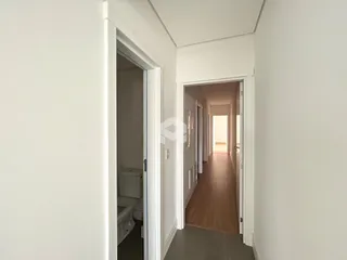 Hall de entrada com piso de madeira e portas brancas.