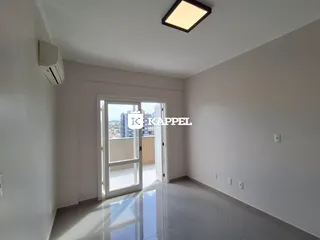 Uma sala de estar clara com porta de vidro que dá acesso a uma vista externa.
