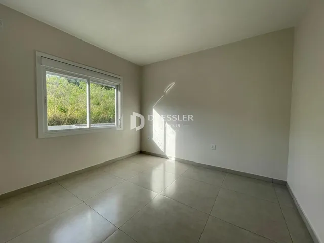 Ambiente interno com piso de cerâmica e grande janela voltada para a vegetação.