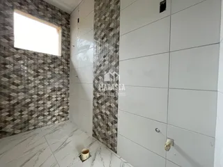 Parede com revestimento de azulejos em padrão diamante e piso de mármore claro em um imóvel.