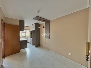 Interior de uma sala de estar com piso de porcelanato claro e armários de madeira.