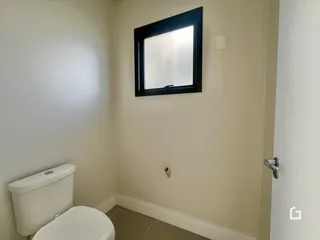 Foto de um banheiro interno com vaso sanitário e parede clara.
