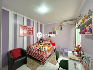 Quarto decorado com cama cheia de brinquedos e um sofá em um ambiente interno.