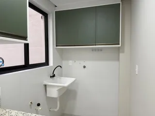 Foto de um banheiro interno com bancada branca e armários superiores.