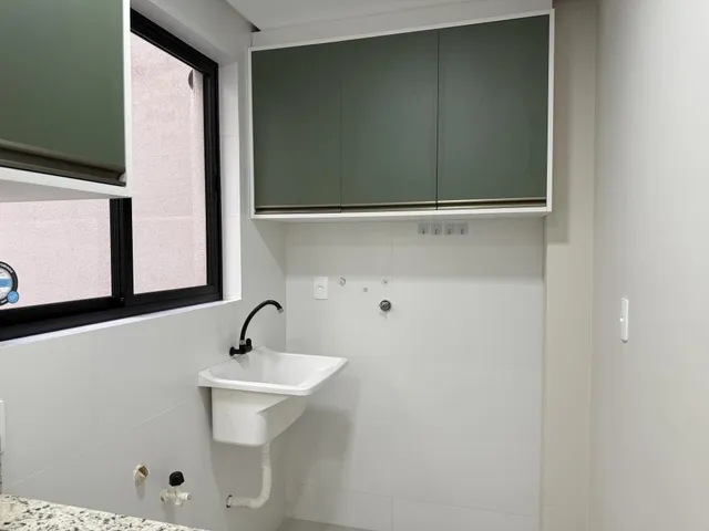 Foto de um banheiro interno com bancada branca e armários superiores.