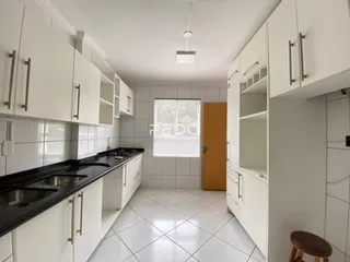 Foto de uma cozinha com armários brancos e piso de cerâmica.
